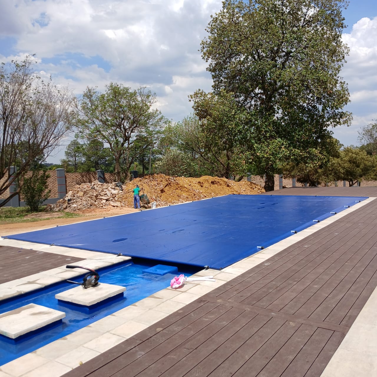 Large blue pool cover fitted beside a timber deck