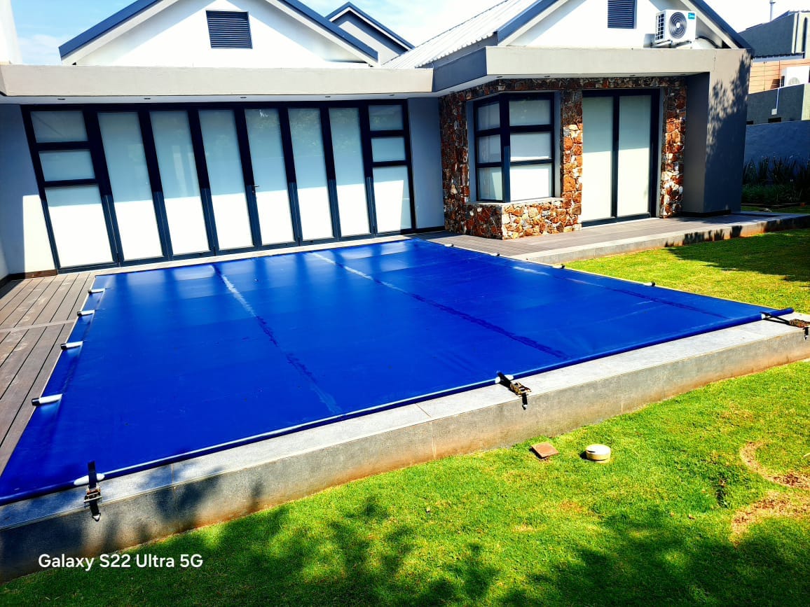 Bright blue pool cover fitted beside a home