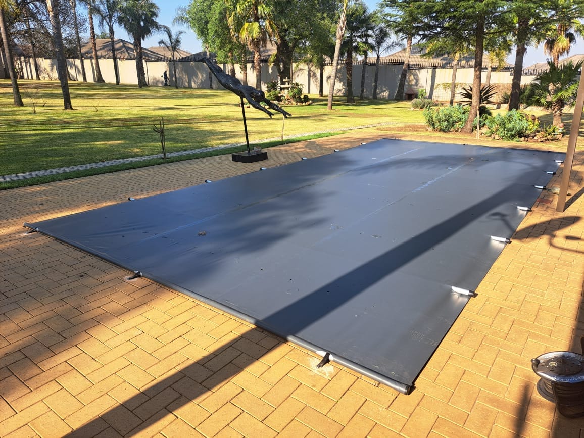 Grey pool cover installed in a landscaped garden